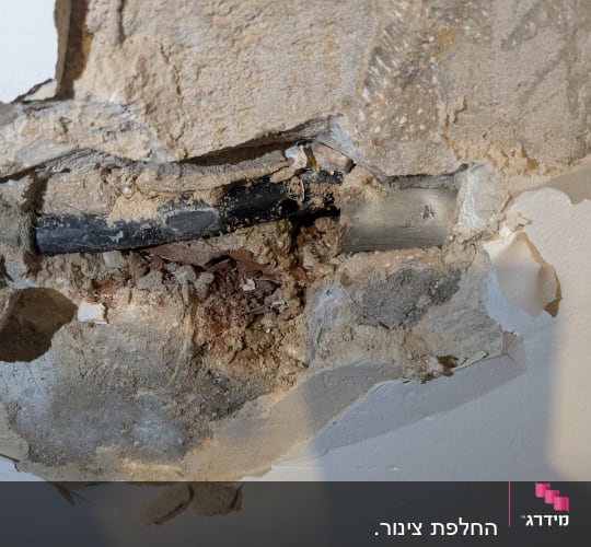 צינור חשוף בקיר עם טיח מתפורר